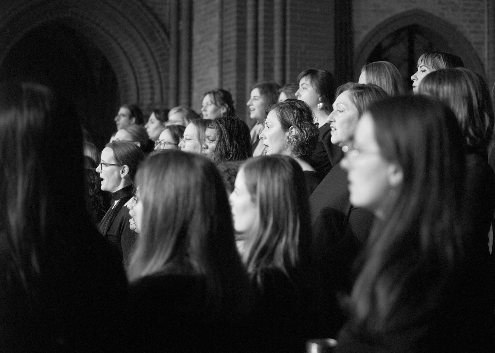 Choir members performing Black and white close up of choir members faces as they perform.